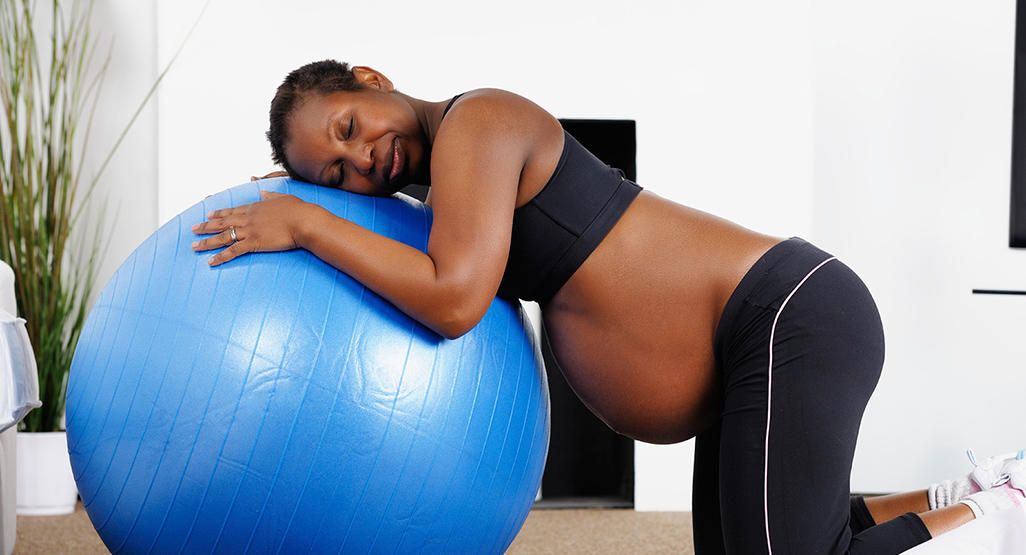 pregnant woman bending over onto a gym ball practicing labor positions