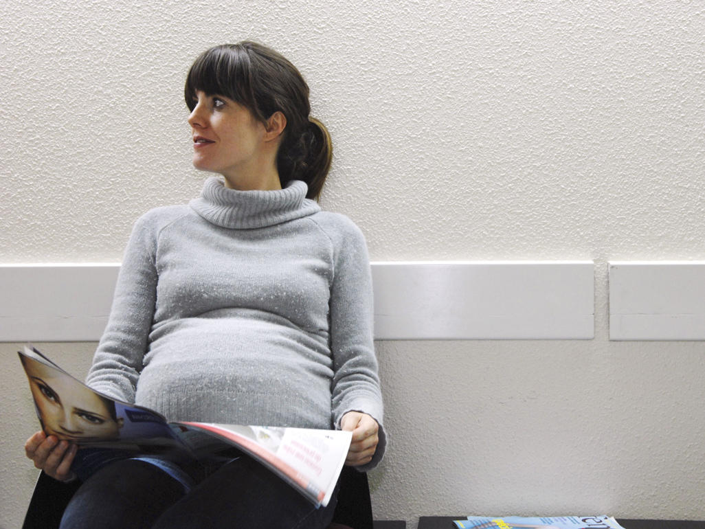 Image contains a pregnant woman sitting in a waiting room