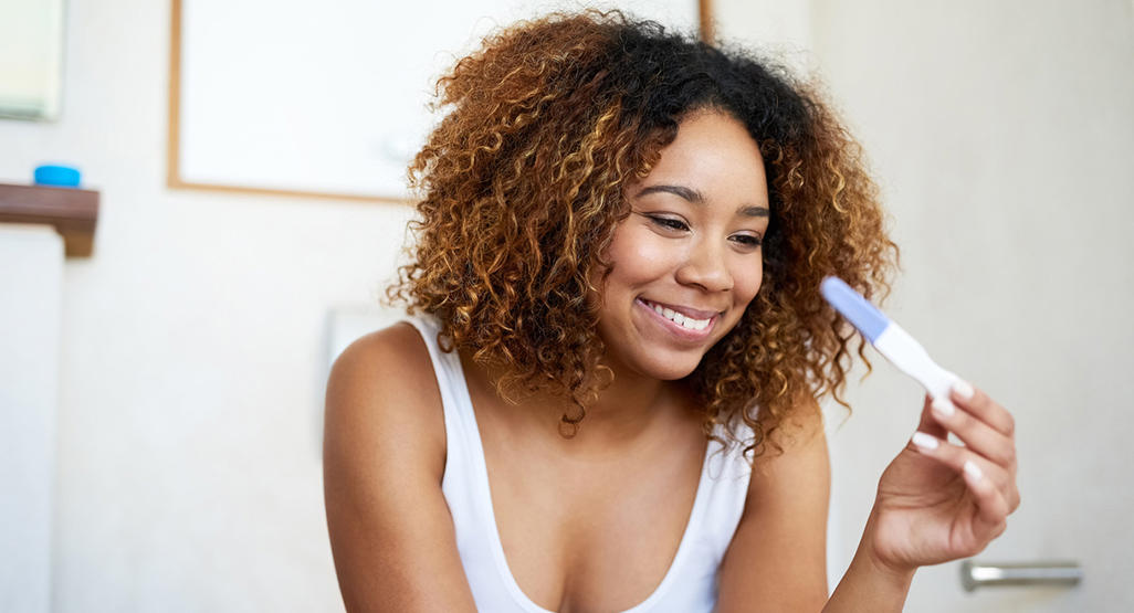 woman looking at a pregnancy test and smiling