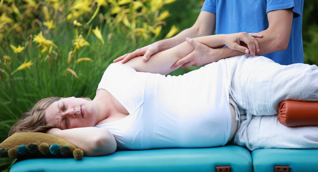 pregnant woman getting an arm massage while lying on her side