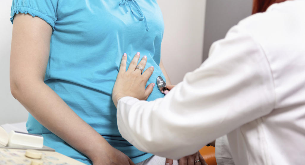 doctor examining a pregnant women's belly with a stethoscope