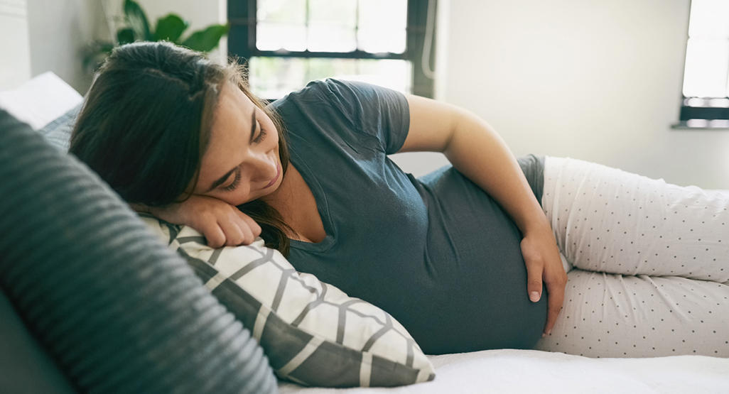 pregnant woman resting in a bed on her right side