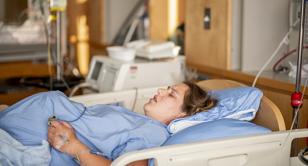 pregnant woman in hospital bed grimacing as if she is in labor