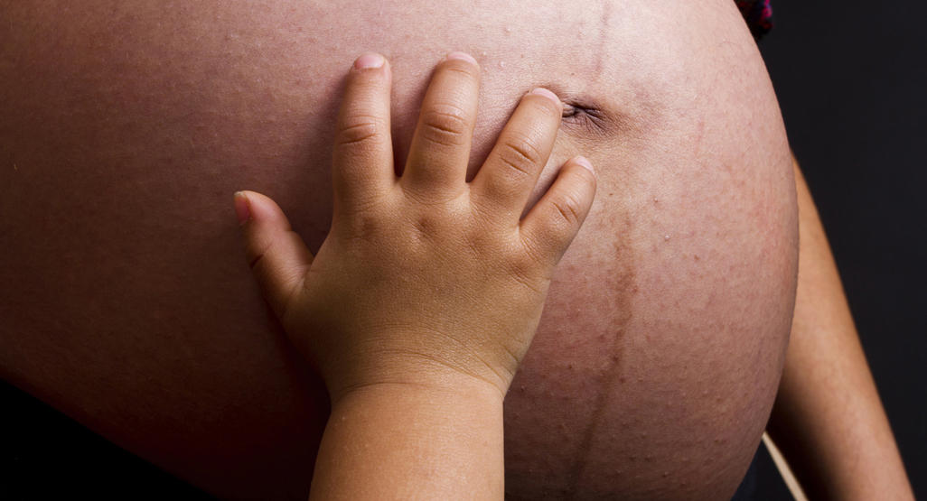 baby's hand on a pregnant woman's belly
