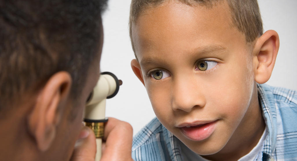 doctor looking into child's eye with a device