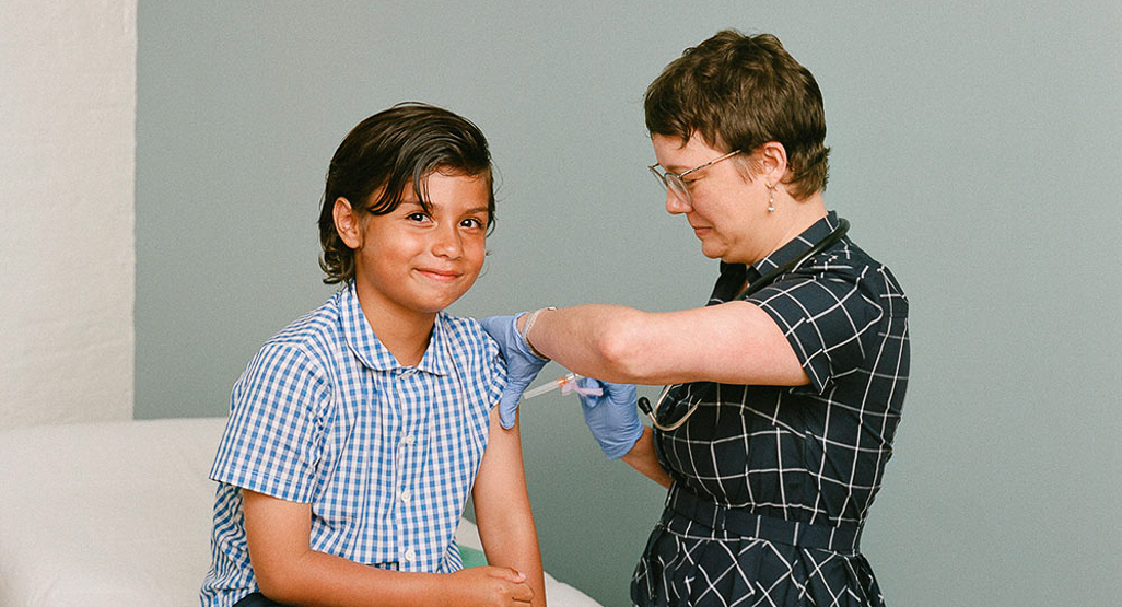 young boy receiving a vaccination in his arm by female medical professional