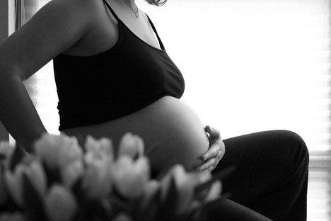 pregnant woman sitting and holding one hand on her belly