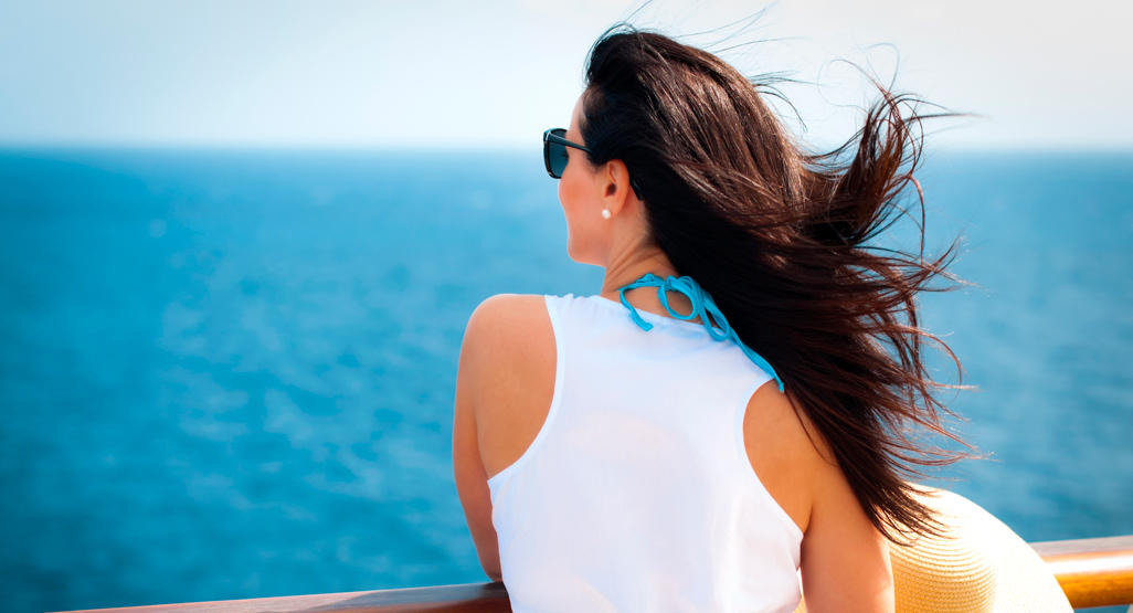 woman standing on a boat deck, looking at the sea, while wind waves her hair