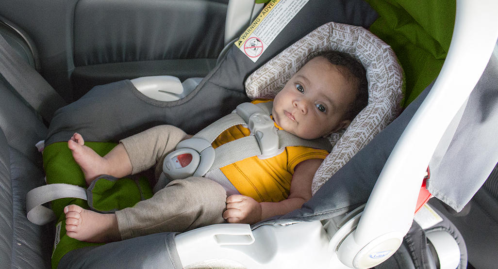 baby with no socks on, sitting in a car seat