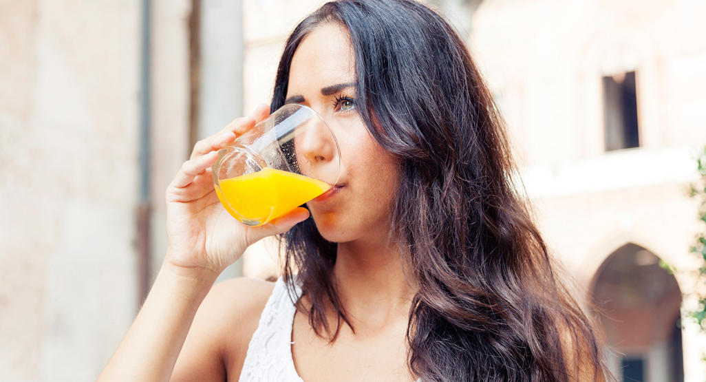 woman drinking a glass of orange juice
