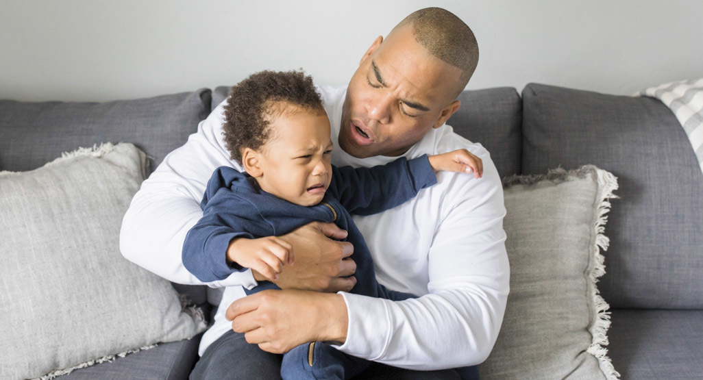 African American dad holding and comforting toddler son