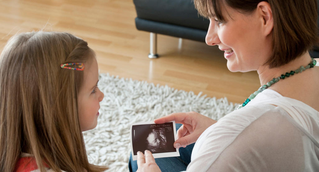 pregnant mother showing her daughter a picture of an ultrasound
