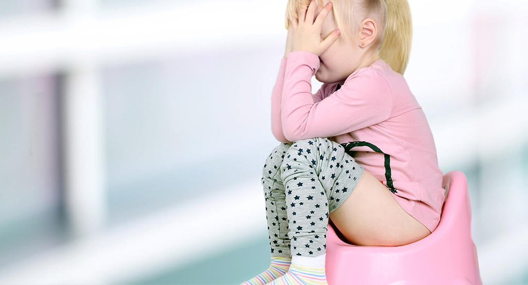 sad toddler touching face on potty pooping