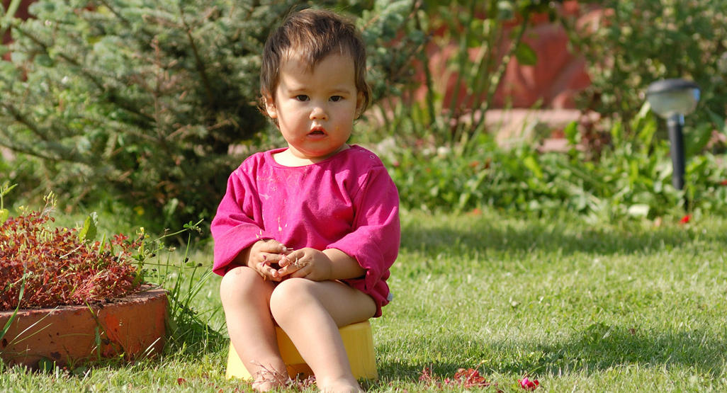 toddler sitting on a potty in the garden