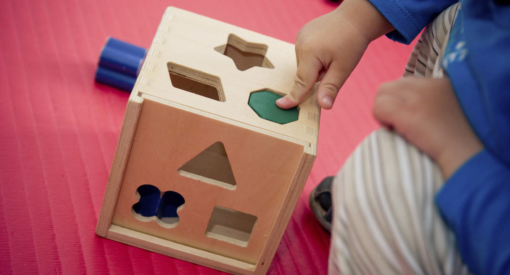 child playing with wooden shape sorter toy