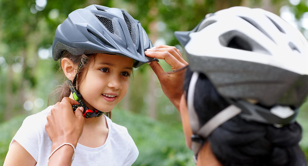 woman adjusting a bike helmet on the girl’s head